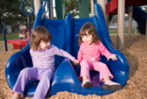 children sliding down a double-slide